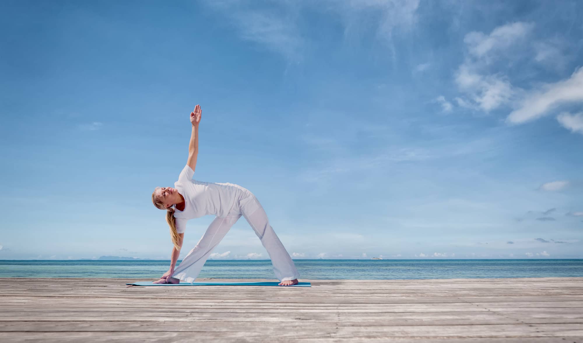 Young man doing yoga exercise - headstand, on a beautiful ...