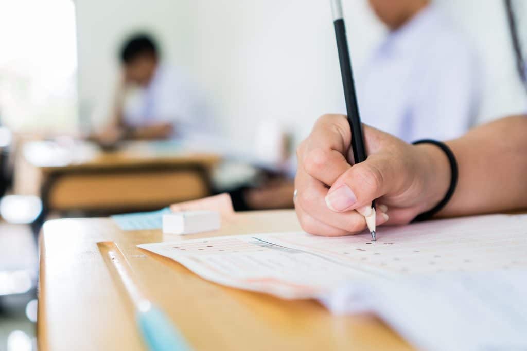 High school university student holding pencil writing exam on paper