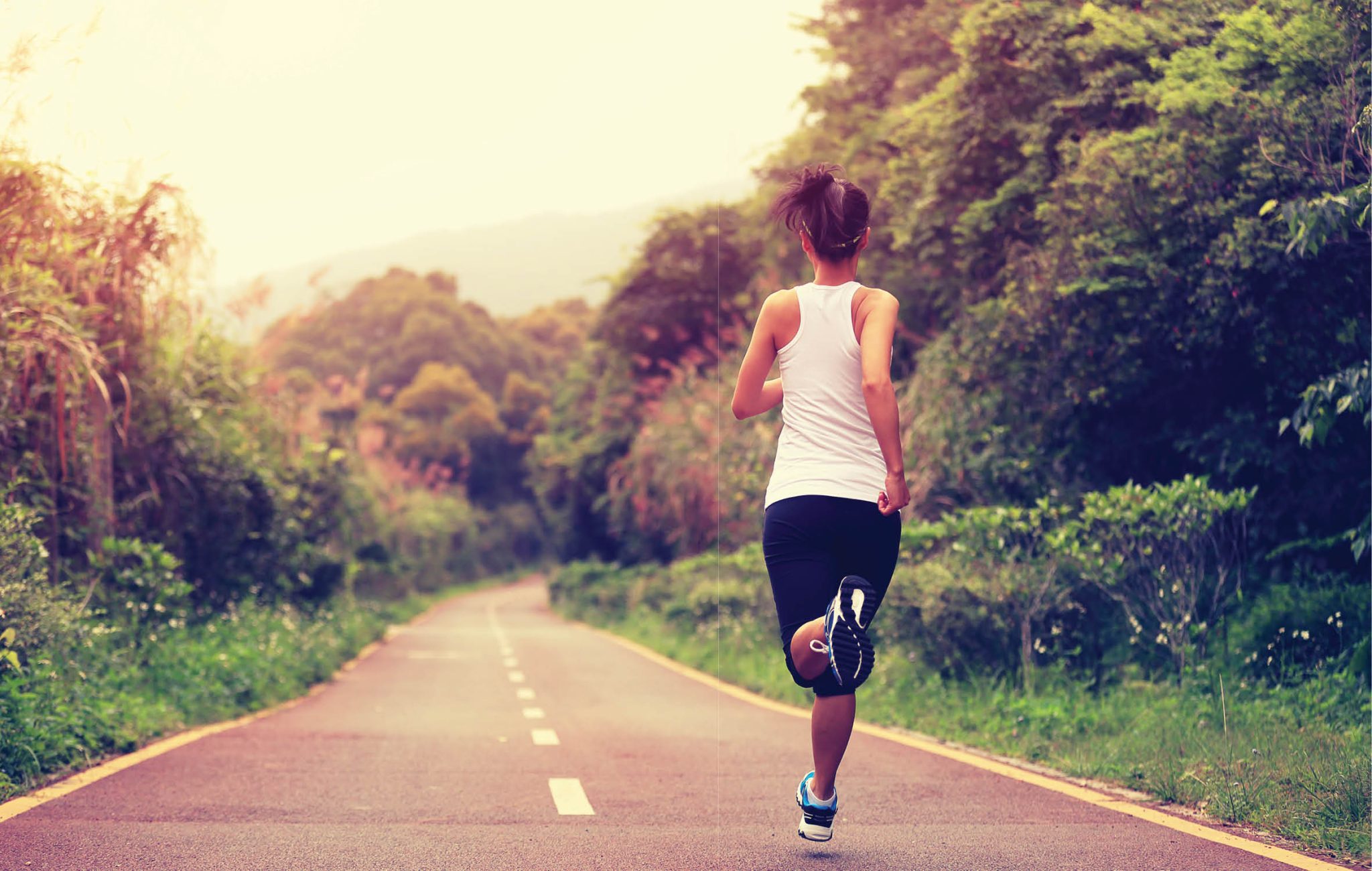Healthy woman exercising and running along road 